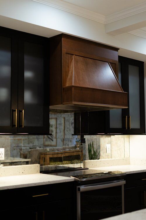 Kitchen remodel with wood oven hood and black cabinets